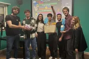 Group of Italian university students standing in front of screen holding prizes and smiling.