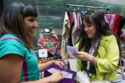 Woman selling clothes and accessories to a smiling client.